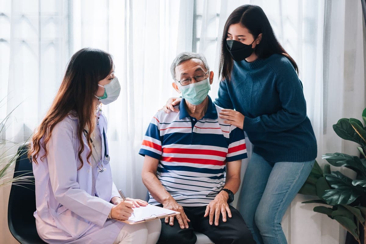 Doctor and family supporting a senior patient at home